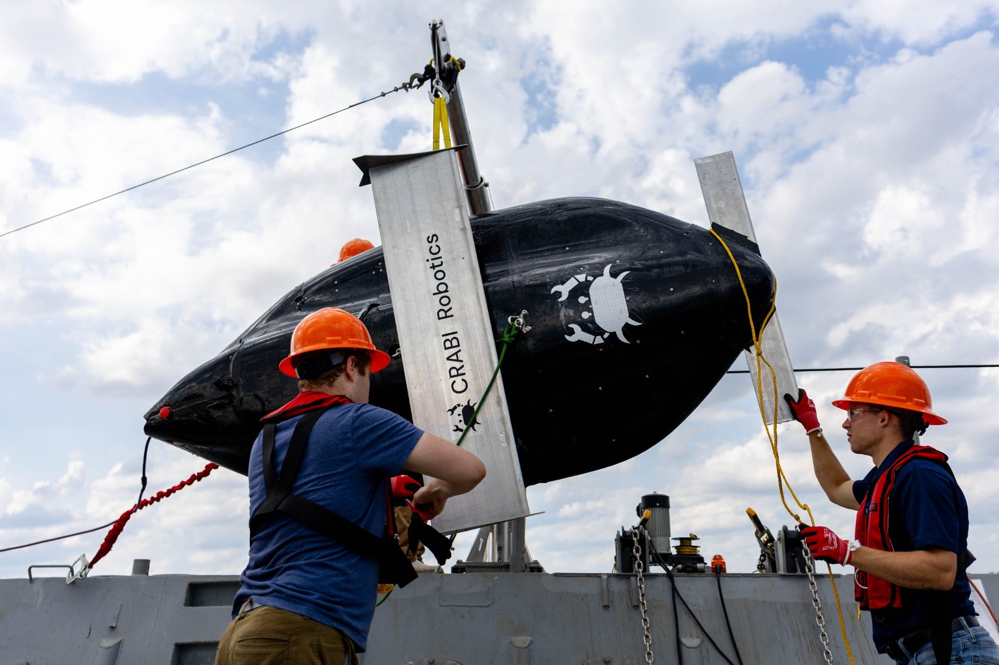 Two team members guiding CRABI into position on deck before deployment